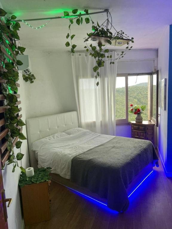 Habitación luminosa con cama doble, plantas y vistas a la montaña